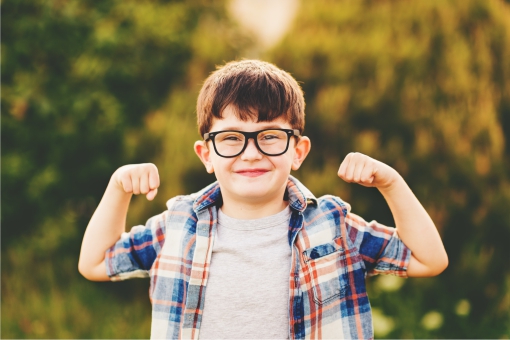 Smart funny boy holding arms up in show of strength